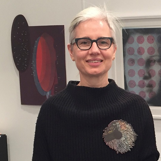 Photo of artist Pia Larsen standing in front of her artwokrs at Sydney Contemporary